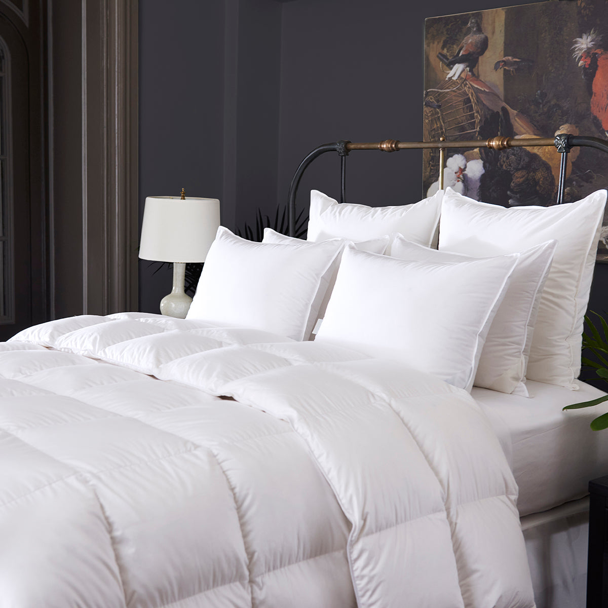 Image of a bed made with a white, fluffy down comforter and many pillows