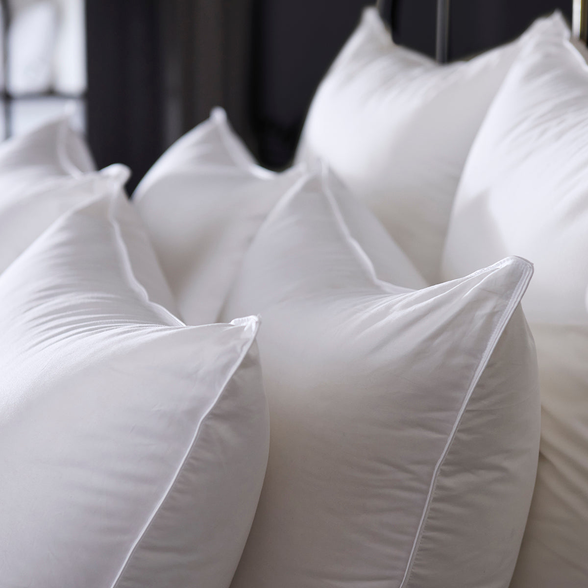 Image of thick, white pillows stacked upright on a bed