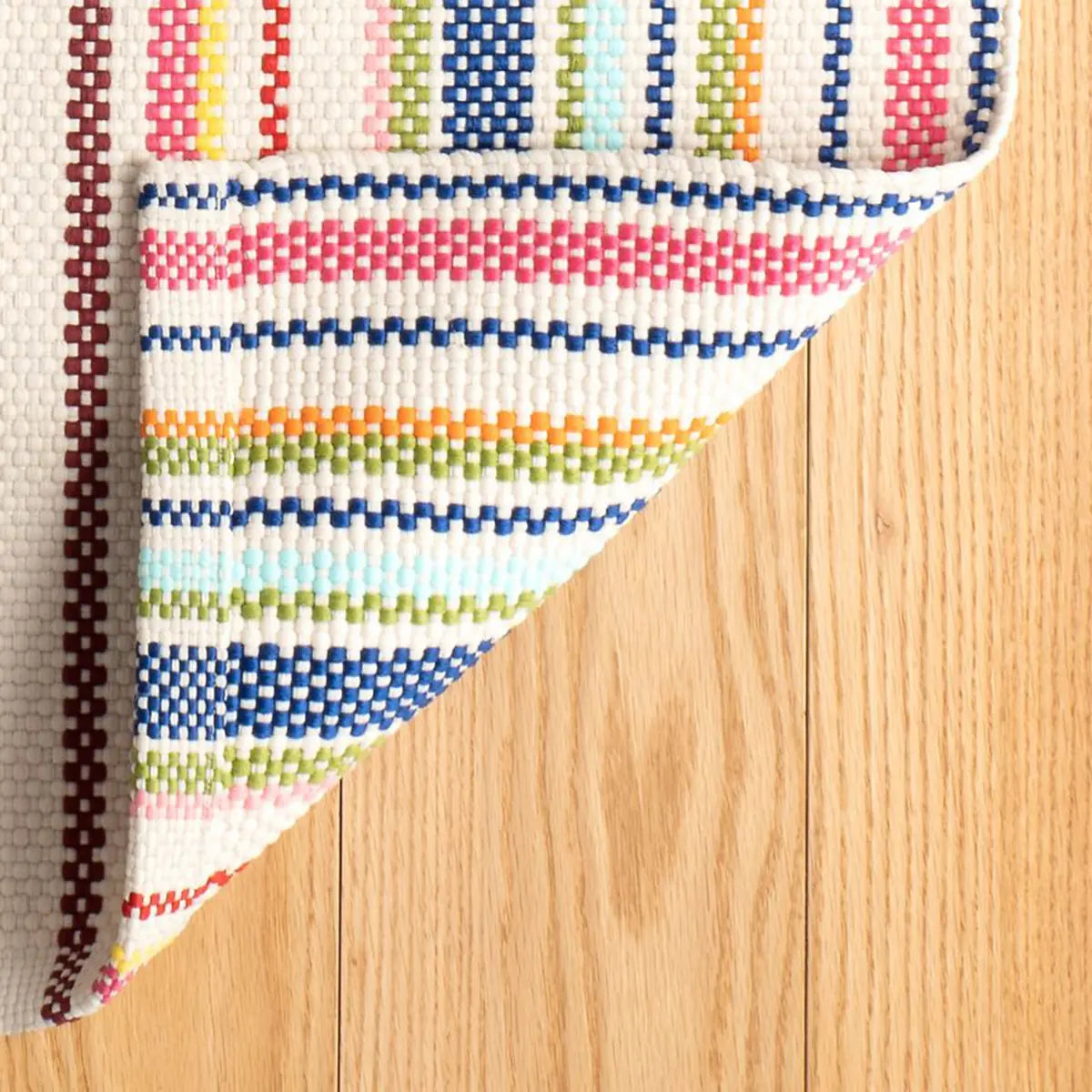 Close up of Dash and Albert Summer Stripe Handwoven Indoor Outdoor Rug with the corner folded up