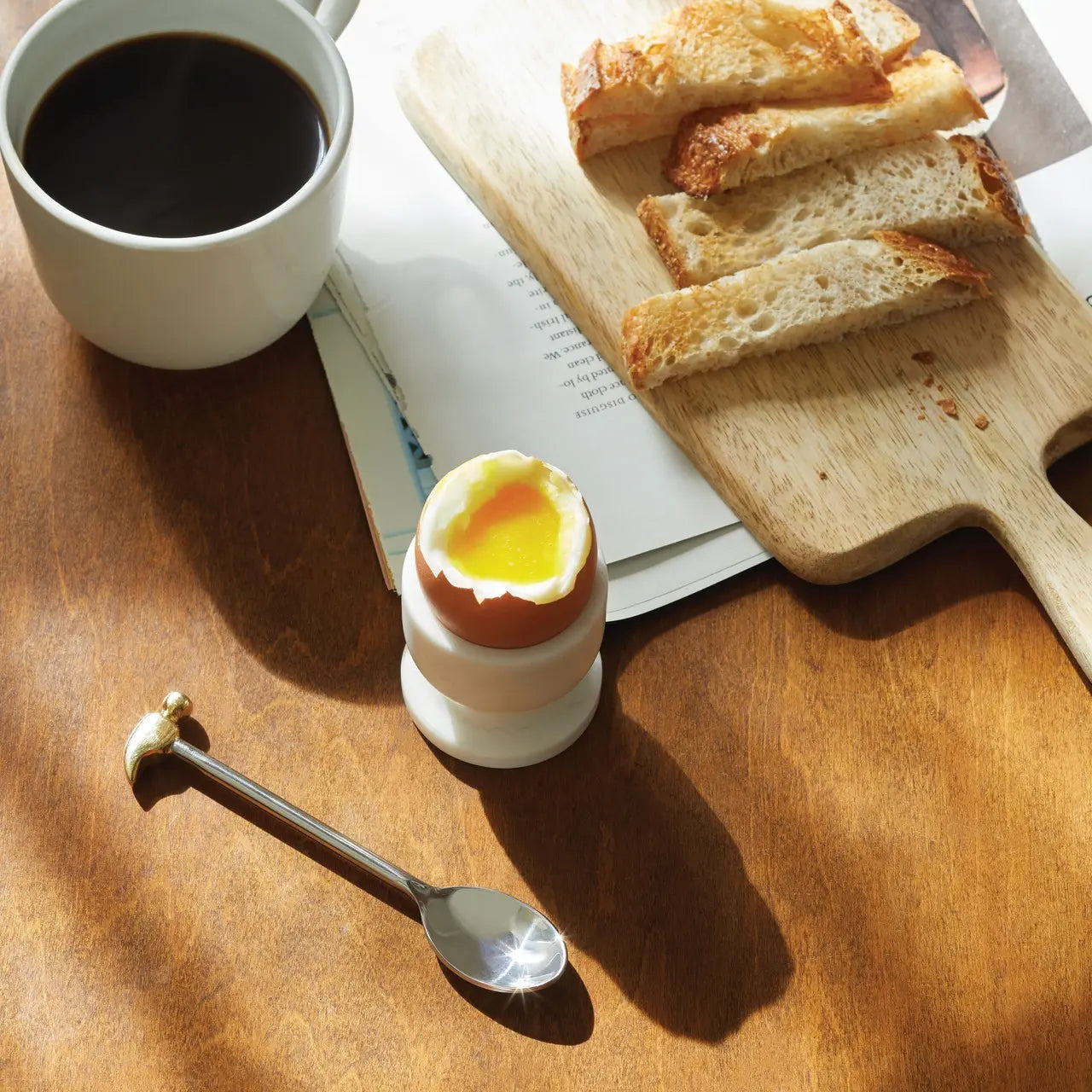 Sir  Madame Egg Spoon AND Hammer in a room with an egg, cup of coffee and bread 