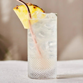Filled Richard Brendon Diamond Highball with a fruit slice and straw on a table