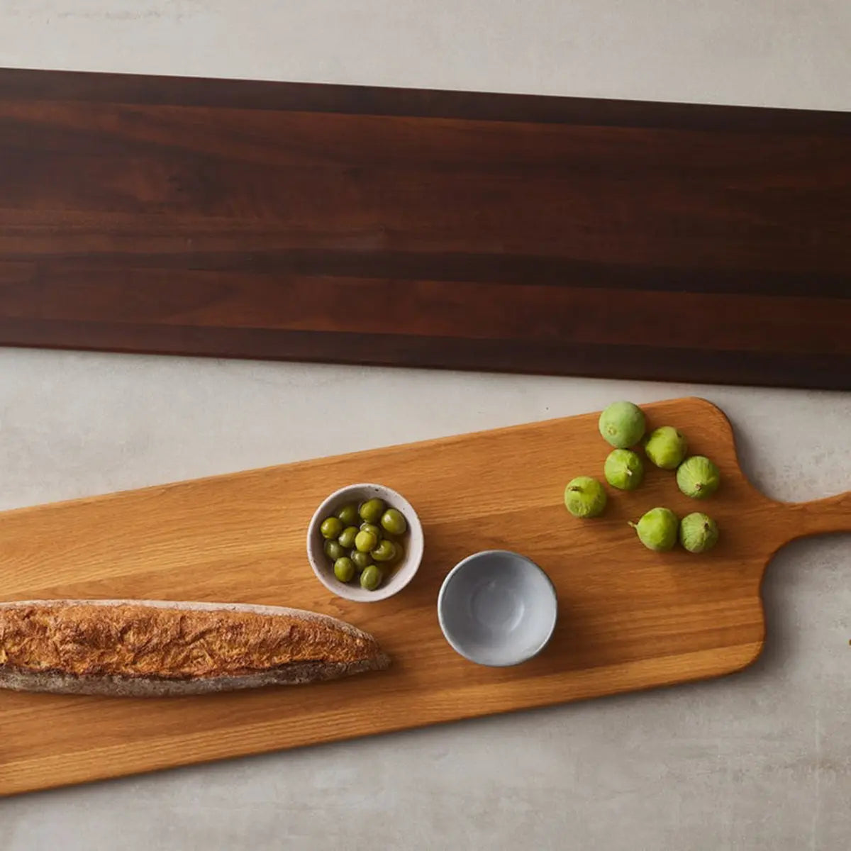Blue Pheasant Edmund Natural Walnut Serving Board in a room with bread, white bowls with olives and food
