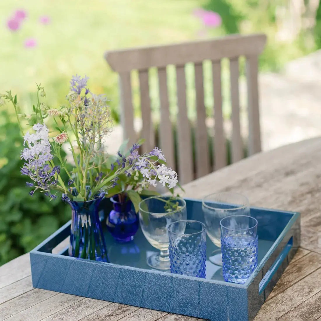 Addison Ross Lacquered Serving Tray in Blue Shagreen set on a table outdoors