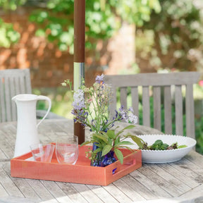 Addison Ross Lacquered Serving Tray in Orange Croc set on a wood table outdoors with glassware and flowers