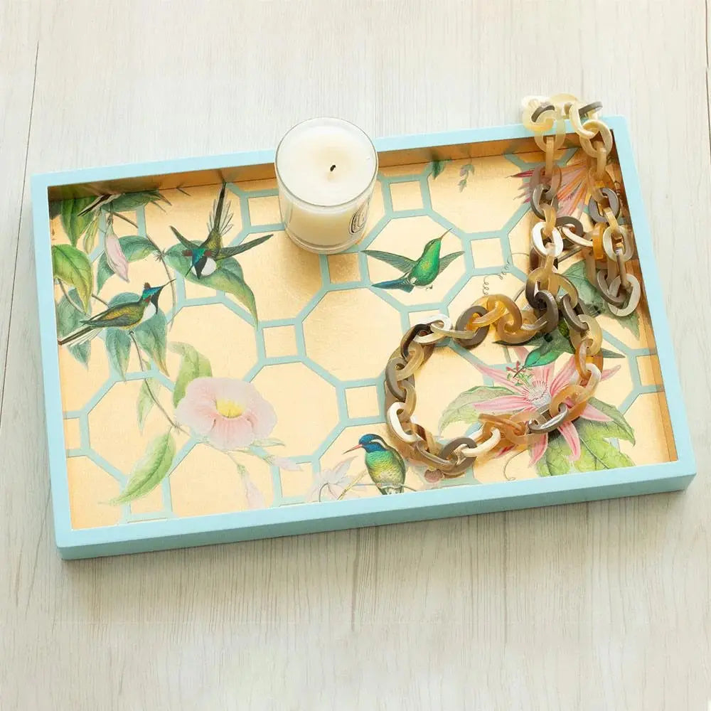 Caspari Hummingbird Trellis Gold Small Rectangular Tray in a room with a candle on top