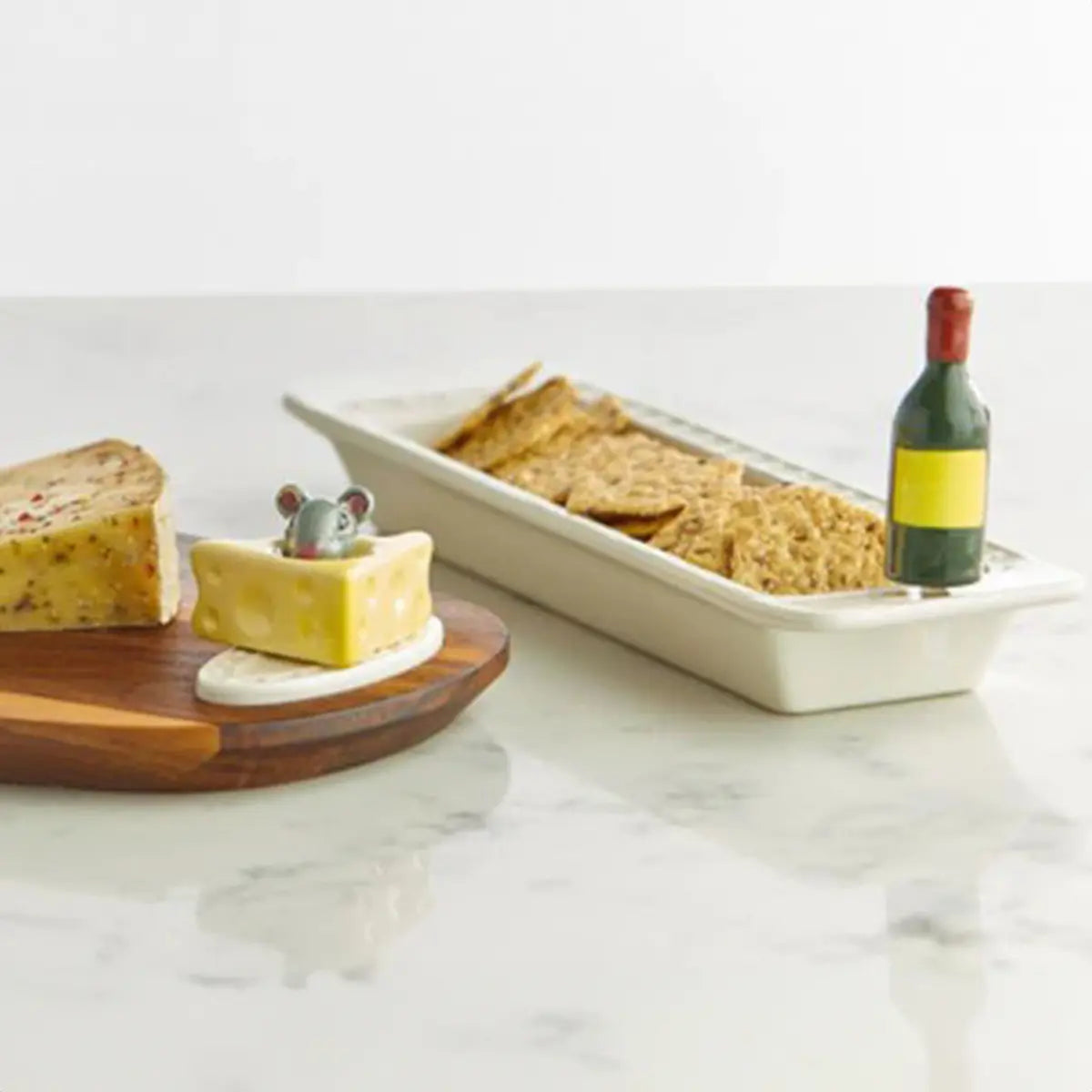Nora Fleming Cheese Please Mini on a wood serving board in a room with food and another tray