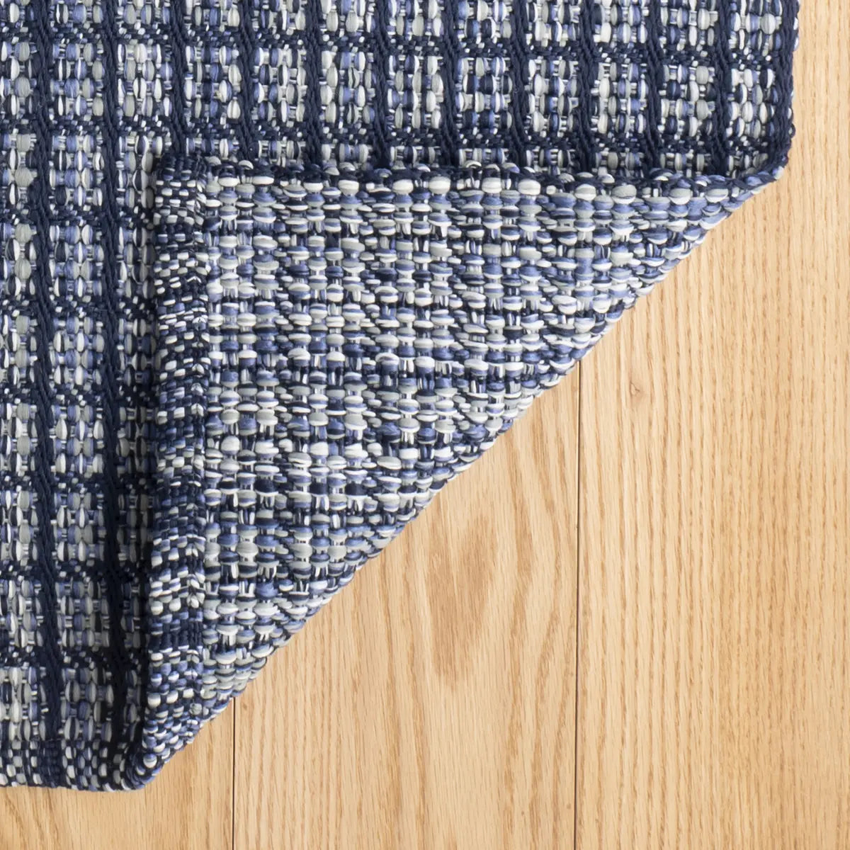 Close up of Dash and Albert Coco Blue Handwoven Indoor Outdoor Rug with corner folded over
