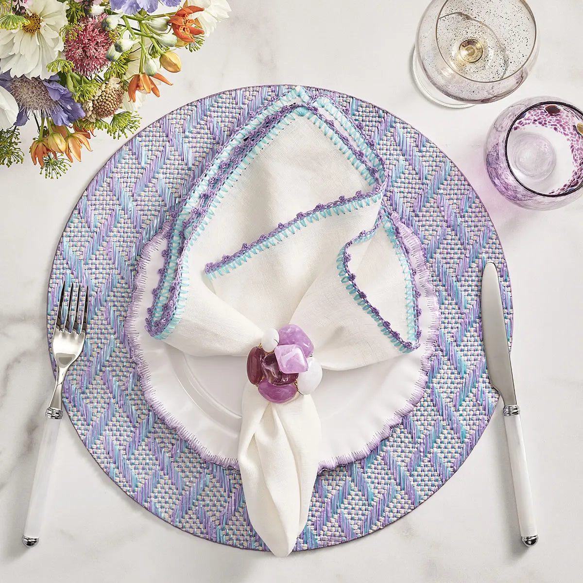 Kim Seybert Knotted Edge Napkin in White Lilac and Blue set on a table