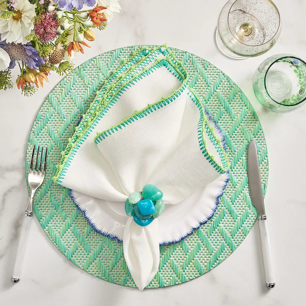 Kim Seybert Knotted Edge Napkin in White Marine and Lime set on a table