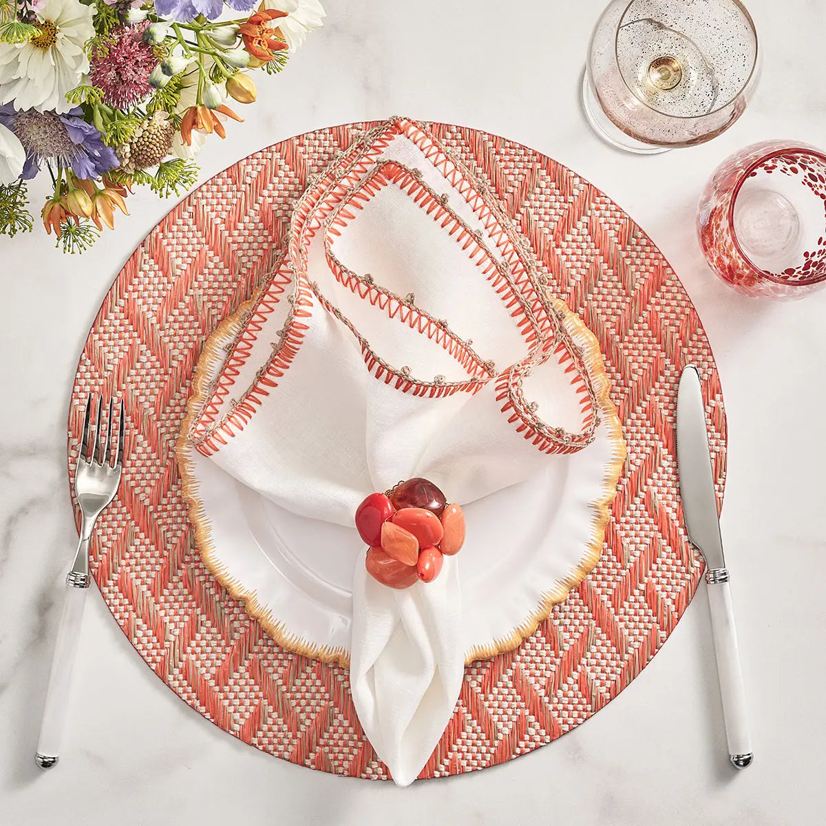Kim Seybert Knotted Edge Napkin in White Natural and Orange set on a table