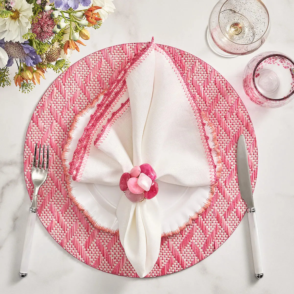 Kim Seybert Basketweave Placemat in Blush Pink set on a table with dinnerware 