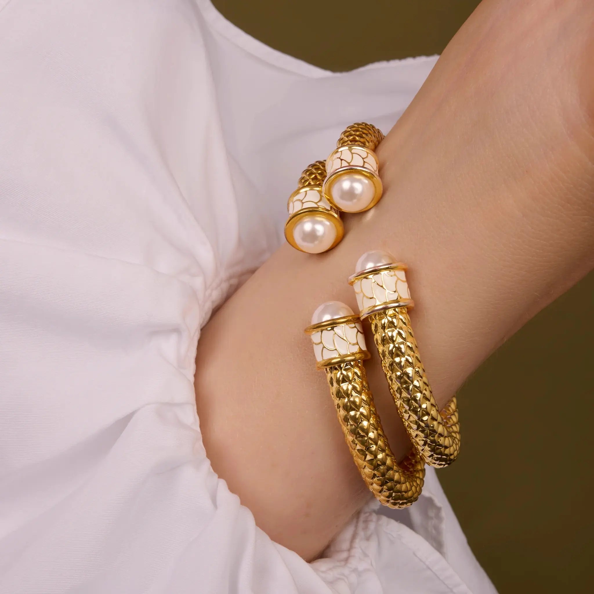 A Woman wearing a pair of Halcyon Days Salamander Torque Bangle in Pearl, Gold