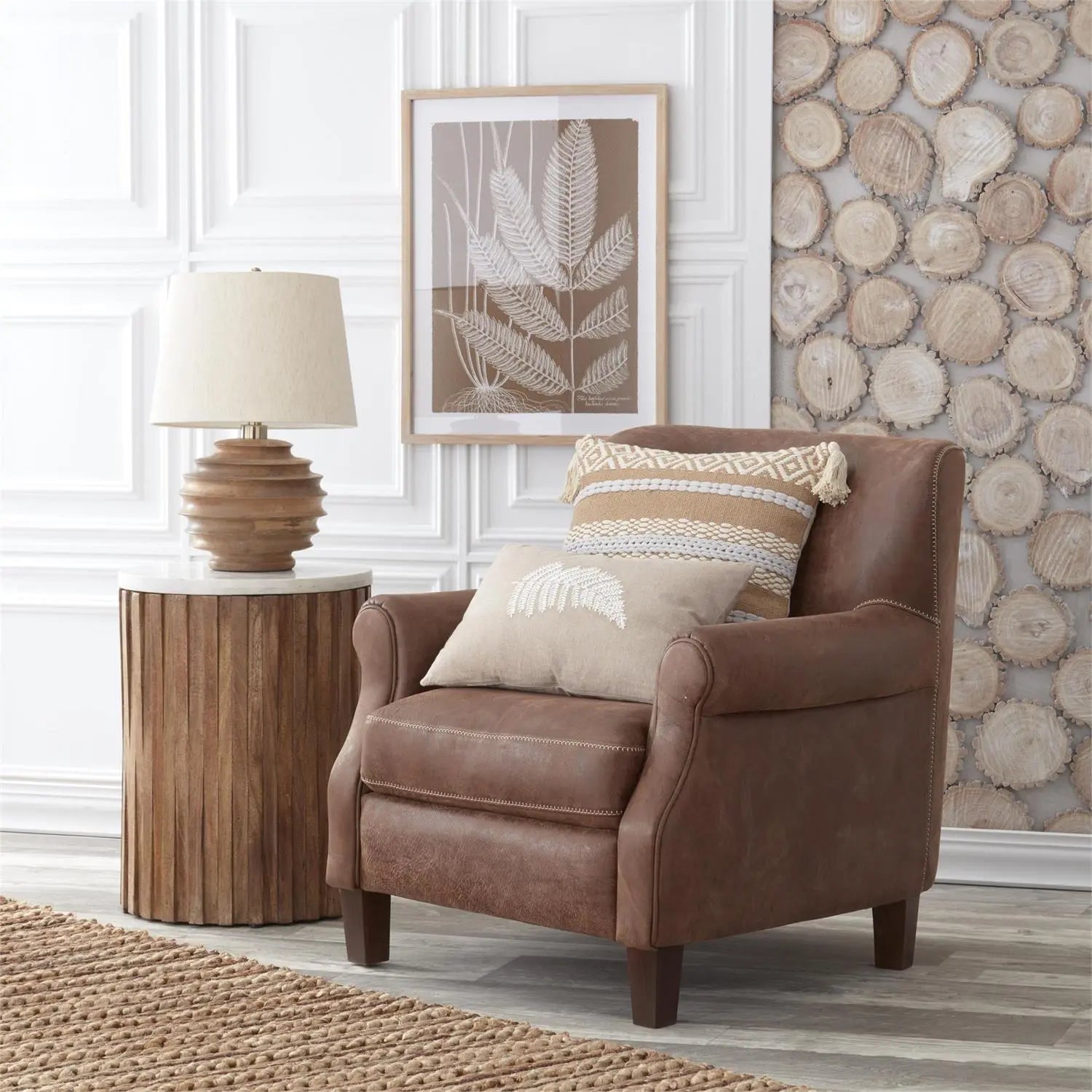 K and K Interiors Mango Wood Ribbed Round Lamp with Shade on a natural wood end table by a brown leather chair with a picture on the wall.