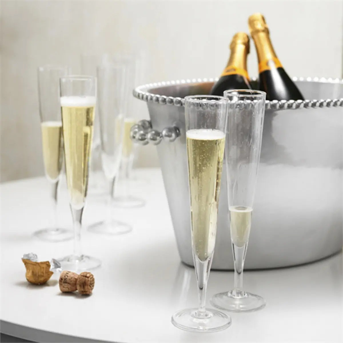 Mariposa Bellini Champagne Flute filled with Champagne next to a ice bucket on a table
