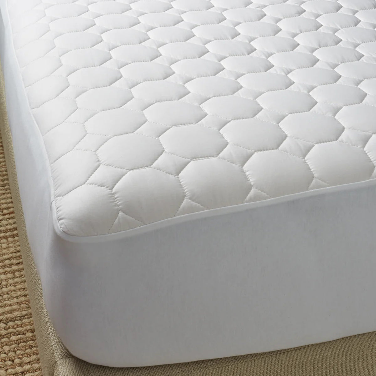 Image of a mattress corner with a white mattress pad covering the mattress