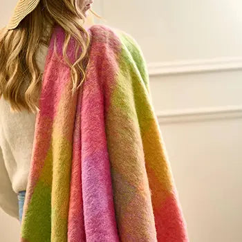 A woman holding Avoca Lotus Mohair Throw in Pink and Yellow over her shoulder