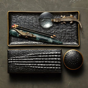 L'Objet Crocodile Magnifying Glass on a decorative black and gold tray with pencils and a letter opener