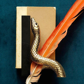 L'Objet Snake Bookend Set with a orange feather on a velvet blue background