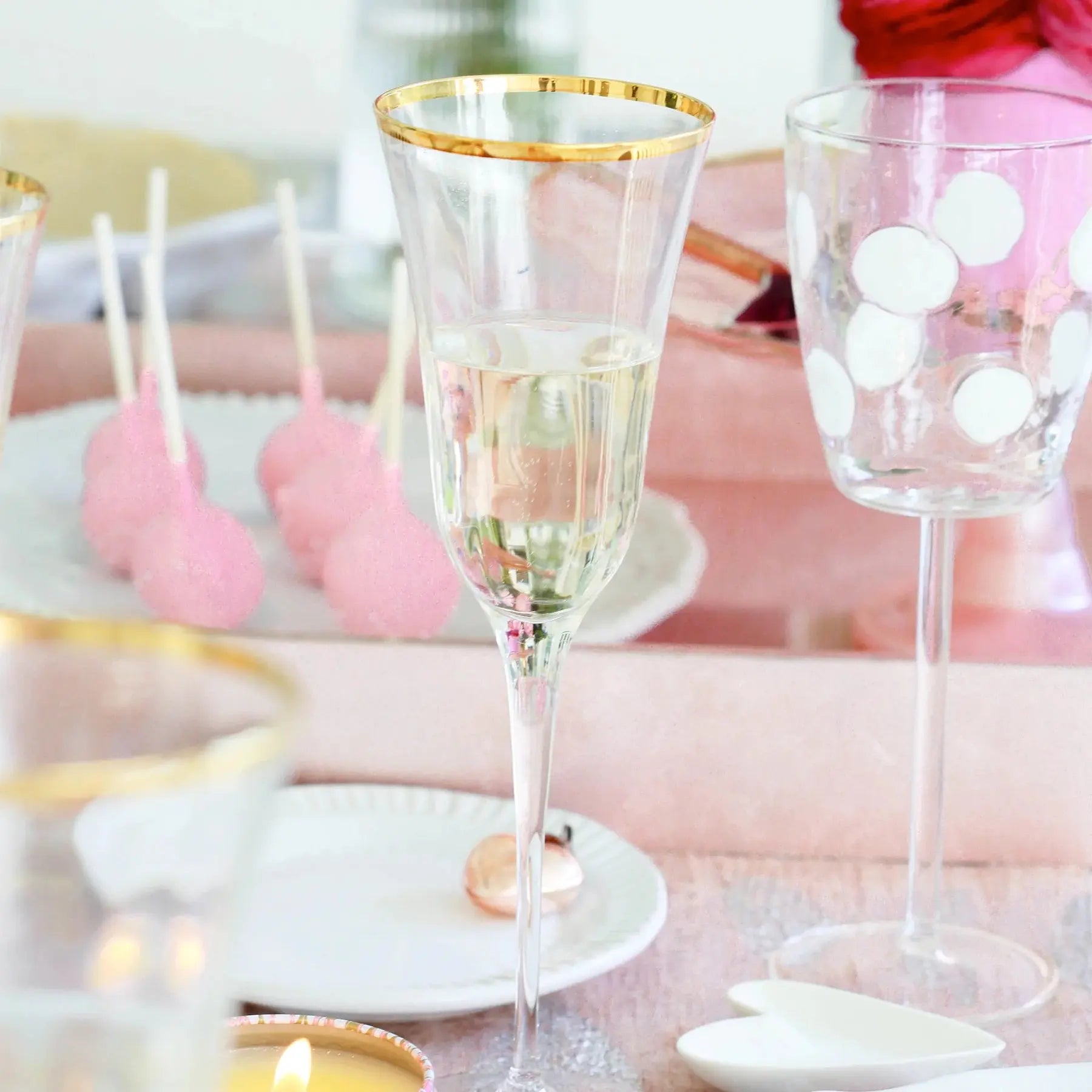 Filled Vietri Optical Champagne Glass on a table set next to cake pops and dessert plates