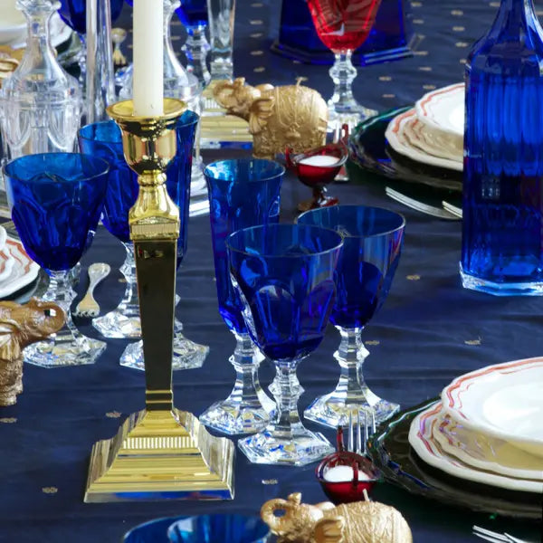 Mario Luca Giusti Dolce Vita Water Goblet and Flutes in blue set on a dining room table with other glassware and items.