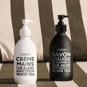 Compagnie de Provence Marseille Black Tea Liquid Soap and white tea cream on a black and white stripe cushion