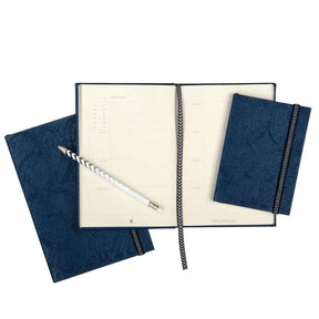 Hachette Christian Lacroix Nuit Paseo Undated Agenda open with a pencile and nuit paseo notebook laid on top and below it.