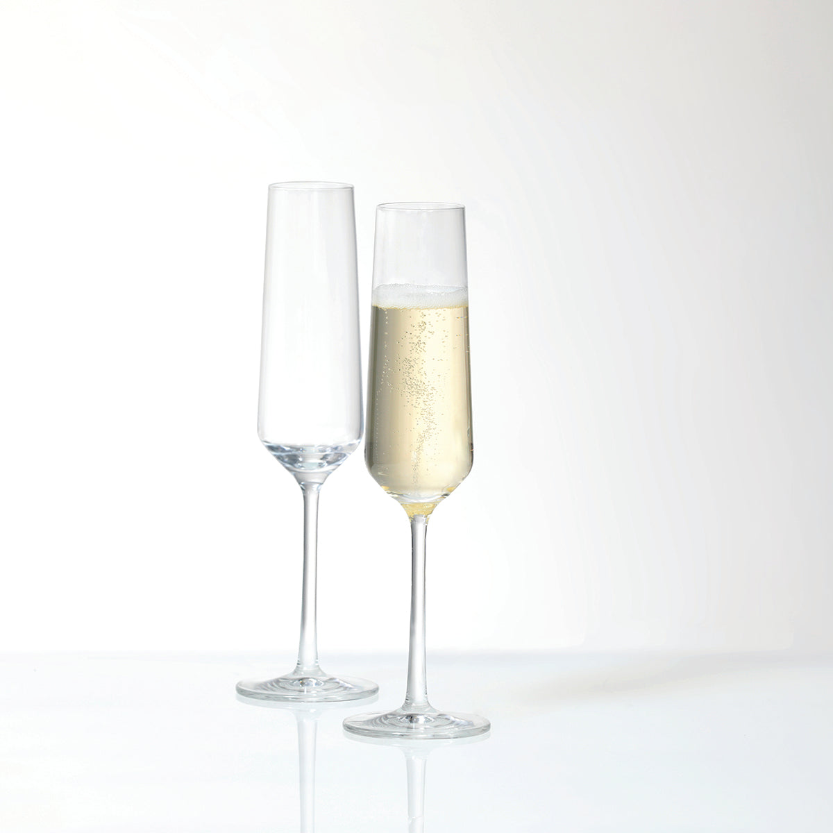 A pair of Fortessa Tritan Pure Champagne Flute with 1 empty and 1 filled with Champagne