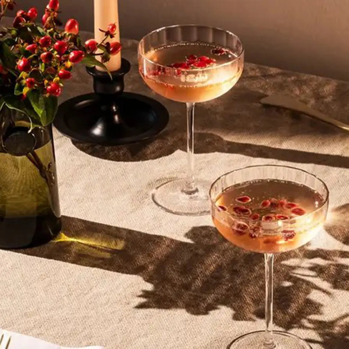 A pair of Richard Brendon Fluted Small Coupe fillled and set on a table next to a bottle