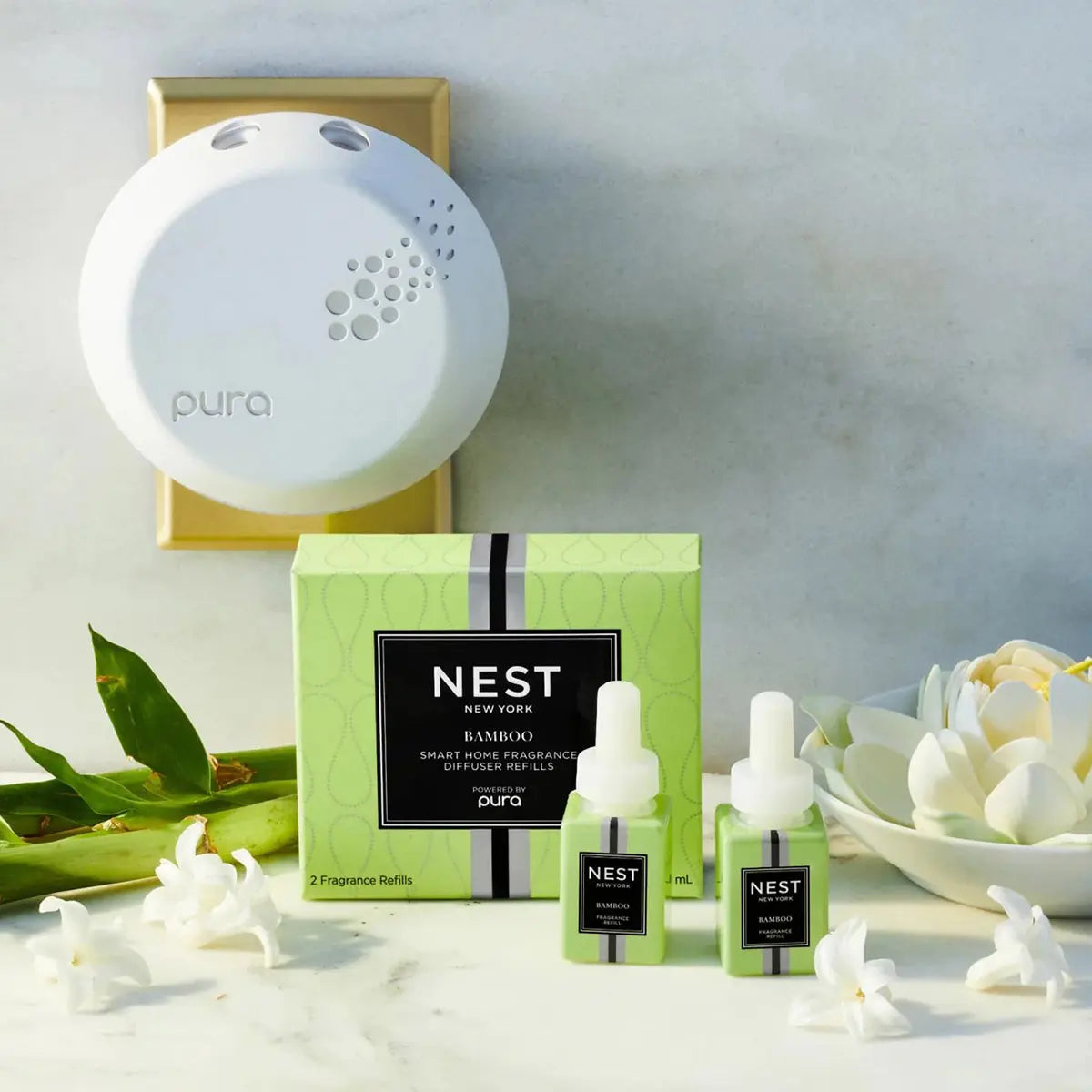 Nest Fragrances Bamboo Pura Smart Diffuser Refill Set of 2 plugged in the wall with the two refills on the table.