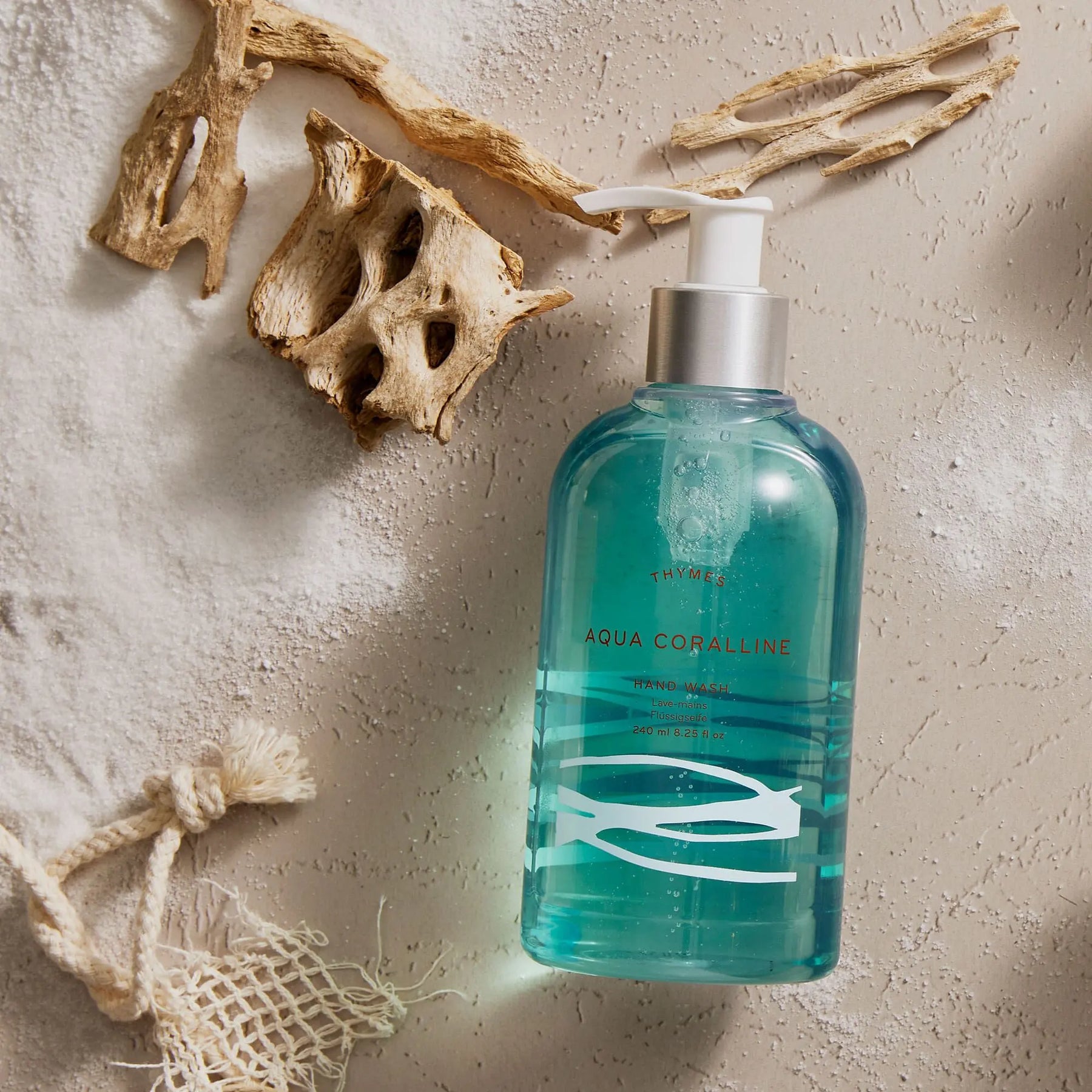 Thymes Aqua Coralline Hand Wash 240 milliliter 8.25 fluid ounce laid on the floor by some driftwood