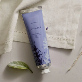 Thymes Lavender Hand Cream 90 milliliter 3 fluid ounce laid on linen fabric and a leaf