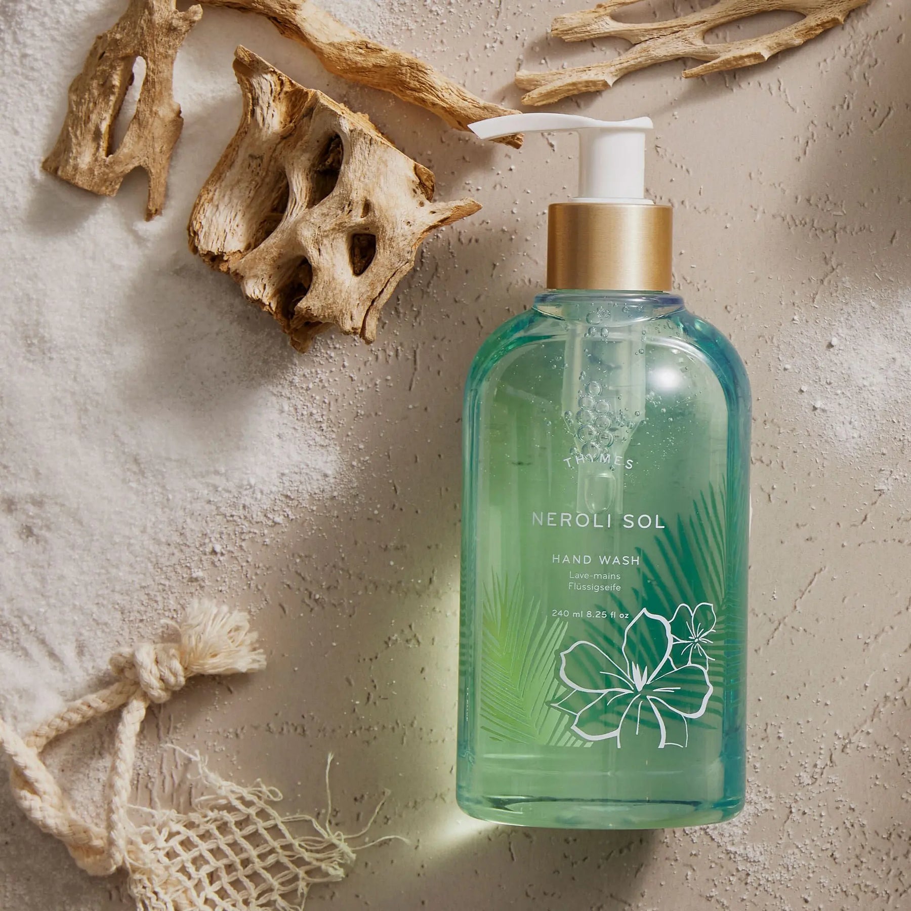 Thymes Neroli Sol  Handwash 240 milliliter 8.25 fluid ounce laid on the floor by some driftwood