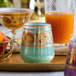 Vietri Regalia Stemless Wine Glass in Aqua set on a gold tray next to other glassware in a room