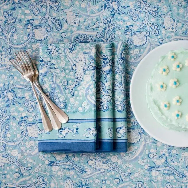 Caravan La Mer Tablecloth with napkins, silver forks and a frosted cake