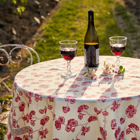 Caravan Cherry Blossom Tablecloth on a round table outside with two filled glasses of wine with flowers and a wine bottle.