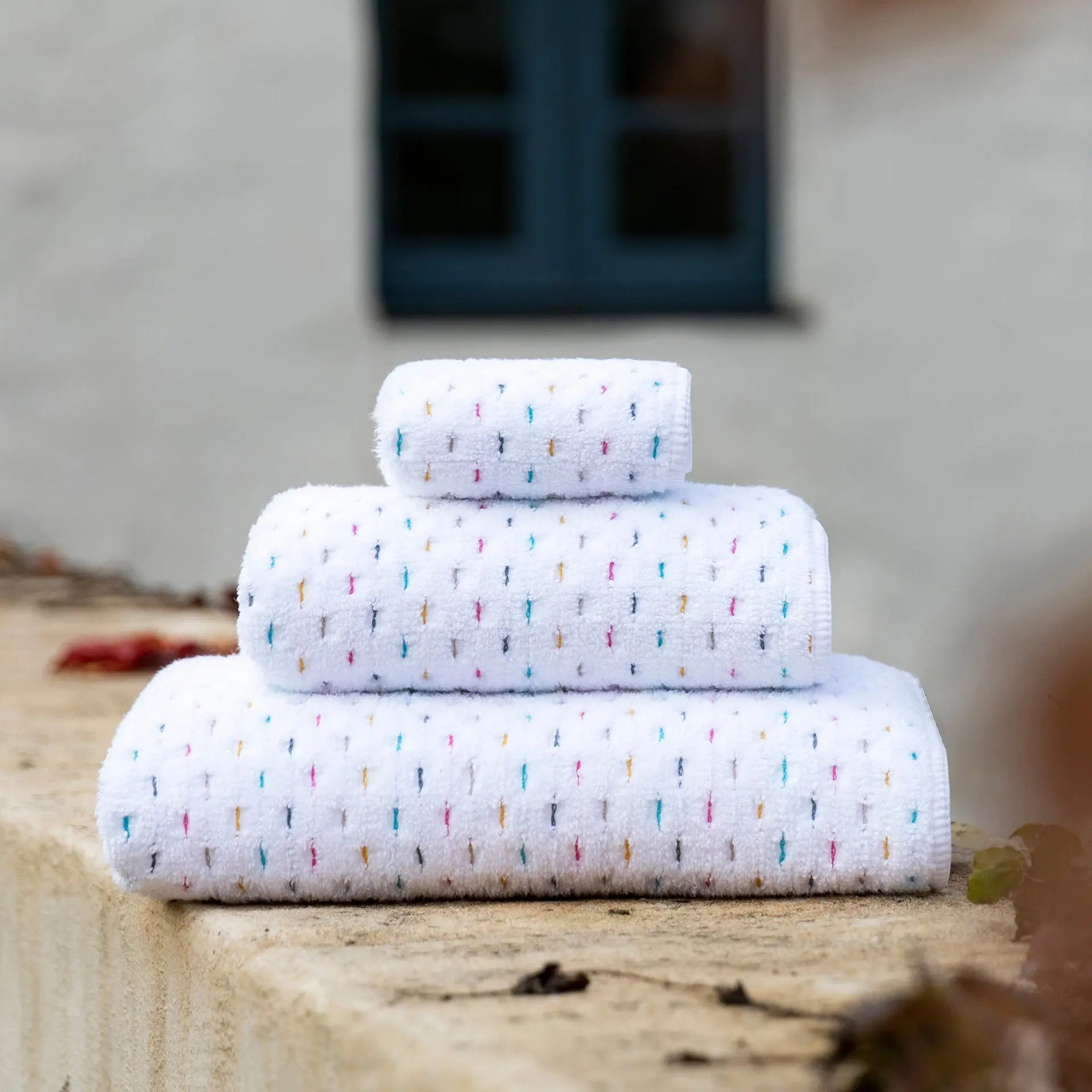 Stack of Graccioza Joy Bath Towels in an outdoor setting on a ledge