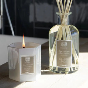 Antica Farmacista Desert Sage HA Diffuser with Reeds next to a lit candle on a table