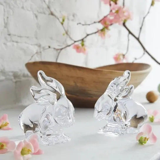 Simon Pearce Glass Rabbit set in a room with pink flowers and a wooden decorative bowl