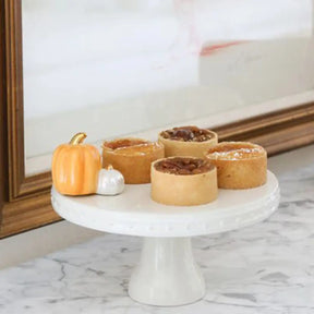 Nora Fleming Pumpkin Spice Mini on a holder with utensils and napkins in a room with two pumpkins