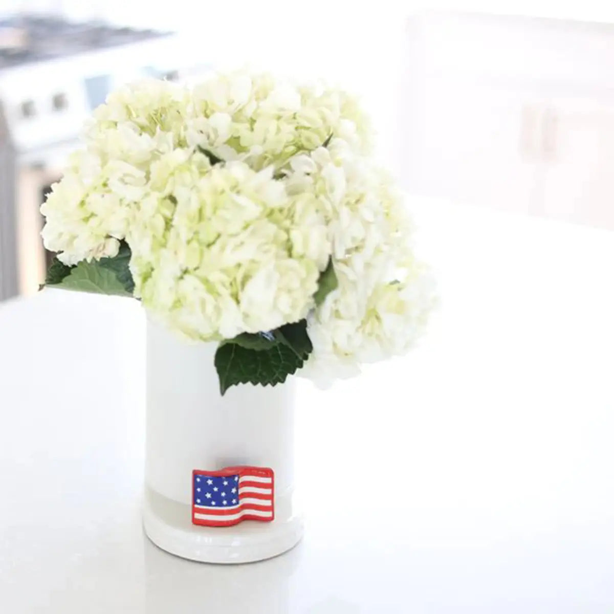 Nora Fleming Stars and Stripes Forever American Flag Mini on a cutie container with flowers in a room