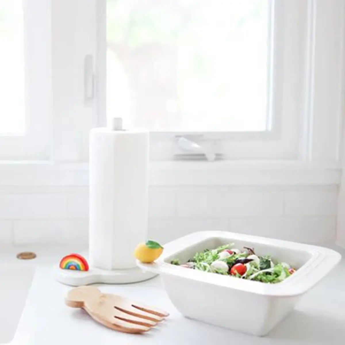 Nora Fleming Over the Rainbow Mini on a towel holder set next to a bowl of salad in the kitchen.