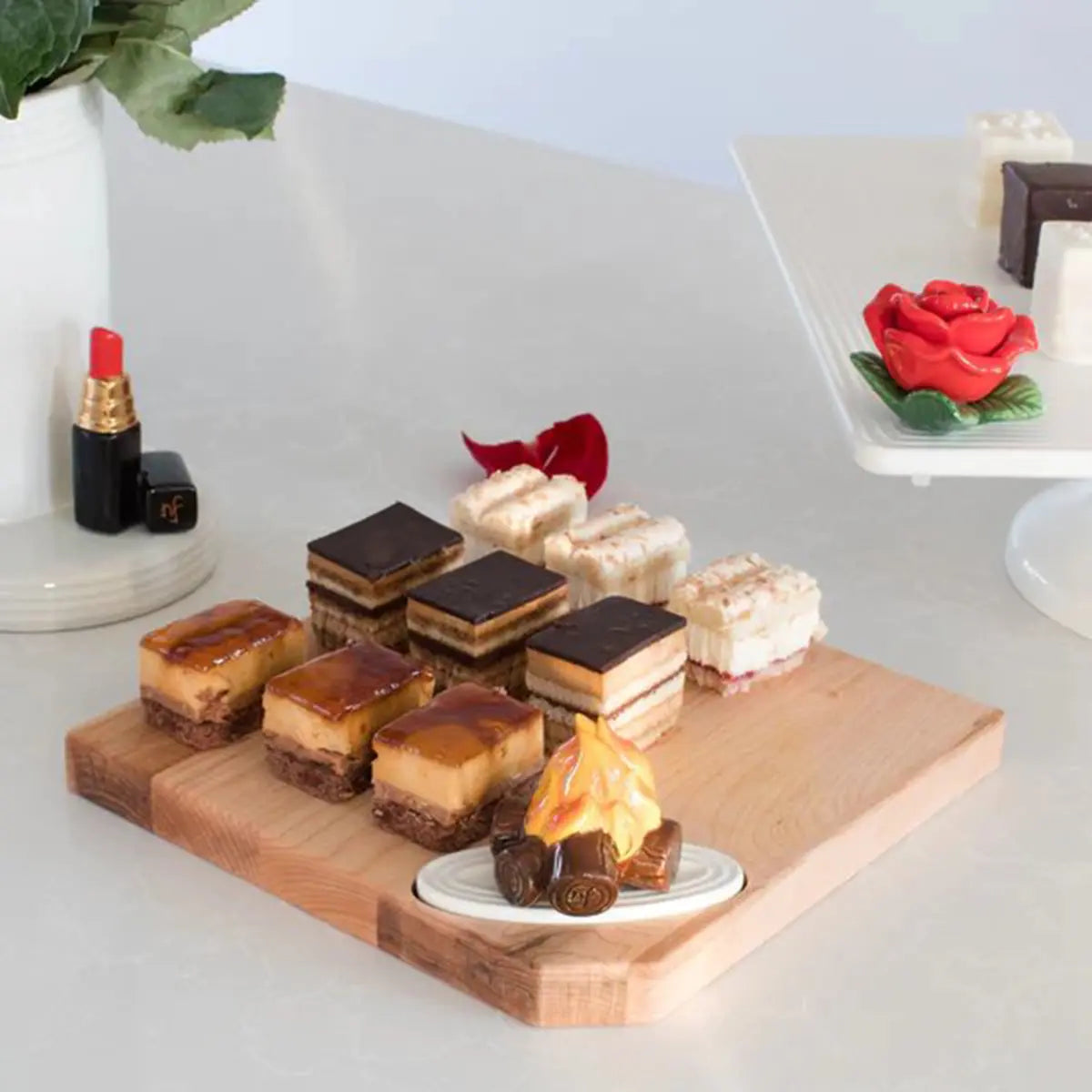 Nora Fleming Hello Gorgeous Lipstick Mini on a container with food and a wooden tray.