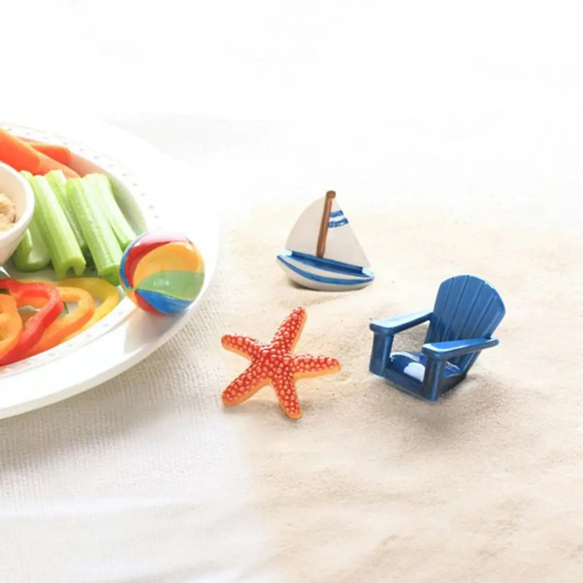 Nora Fleming Sea Star Starfish Mini on the sand next to the Adirondack chair, sail boat and a plate of food