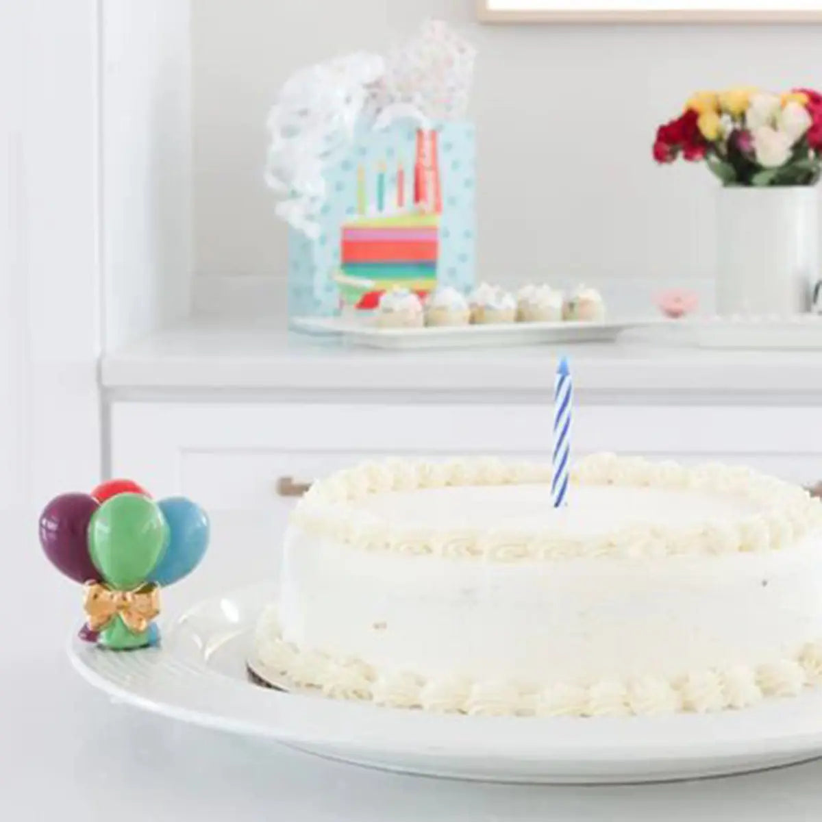Nora Fleming Pinstripes Round Server in the kitchen with a white frosted cake on top and birthday balloon mini.