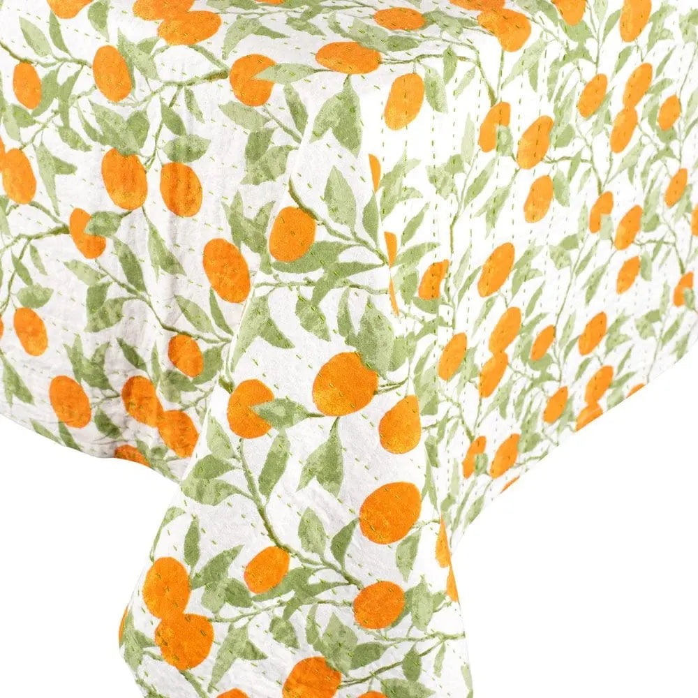 Caspari Reversible Orange Grove Kantha Table Cover draped on a table