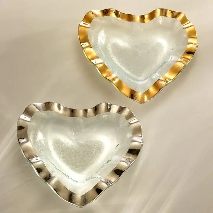 Annieglass Ruffle Heart Bowl in clear gold and clear silver laid on a table 