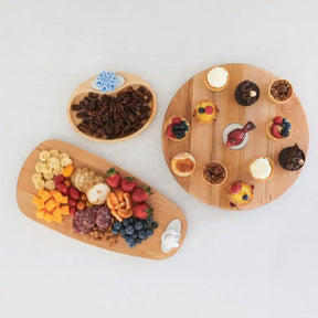 Nora Fleming Maple Lazy Susan with a red bird mini and mini pastries and two other serving boards with food.