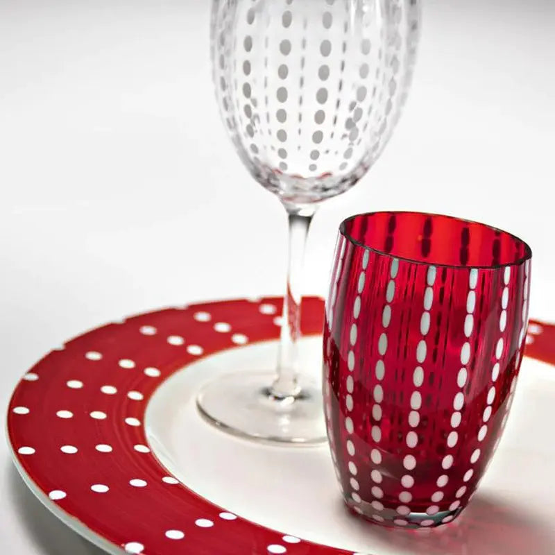 Zafferano America Perle Red Tumbler and Clear Wine Goblet on a dinner plate
