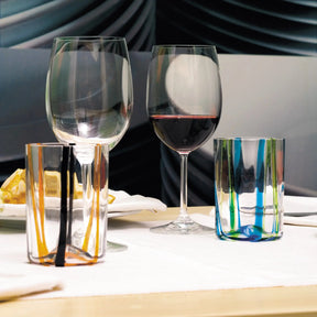 Zafferano America Tirache Tumblers in Orange and black as well as Aquamarine and Green on a dining room table with wine glasses and food