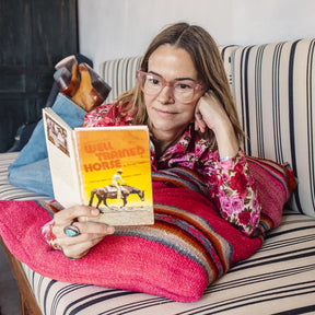 Woman wearing Caddis Dohbro Readers - Matte Pink while reading a book